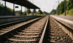 Bahngleise mit Schotterbett und Bahnsteig bei hellem Tageslicht, fotografiert mit Tiefenschärfe.