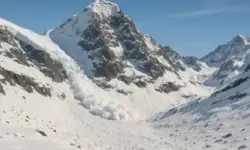 Schneebedecktes Bergmassiv mit einer herabgehenden Lawine im hochalpinen Gelände unter blauem Himmel.