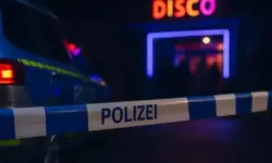 Polizeiauto und blau-weißes Absperrband vor einem unscharfen Discoeingang bei Nacht.