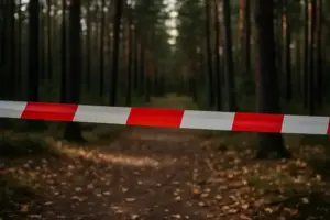 Absperrband vor einem Waldweg in einem herbstlichen Wald, mit unscharfem Hintergrund und natürlichem Licht.