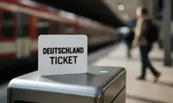 Deutschlandticket-Karte auf einem Fahrkartenentwerter am Bahnsteig mit unscharfer Bahn und Personen im Hintergrund.