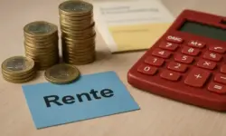 Gestapelte Euro-Münzen, ein roter Taschenrechner und eine Karte mit der Aufschrift „Rente“ auf einem Holztisch.
