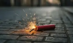 Feuerwerksreste liegen auf nassem Asphalt im warmen Licht einer Straßenlaterne, keine Menschen im Bild.