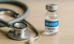 Stethoskop und Impf-Vial auf einem Tisch in hell ausgeleuchtetem medizinischem Umfeld, ohne Menschen.