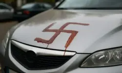 Nahaufnahme einer Autokarosserie mit einem aufgemalten Hakenkreuz, aufgenommen bei Tageslicht, ohne erkennbare Personen.