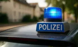 Nahaufnahme eines Polizeiwagens mit blauem Blaulicht und dem Schriftzug „Polizei“ auf dem Dach, im Hintergrund unscharfe Wohnhäuser.