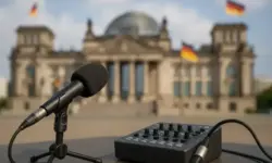 Mikrofon und Mischpult auf einem Tisch mit dem unscharf im Hintergrund sichtbaren Reichstagsgebäude in Berlin.