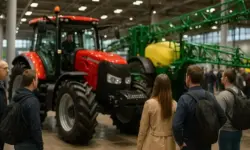 Besucher stehen in einer Messehalle vor einem roten Traktor mit grünem Sprühsystem und betrachten die Landmaschinen.