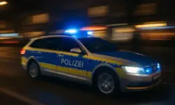 Nächtliche Innenstadtstraße mit Absperrband und Blaulicht-Reflexionen auf nassem Pflaster.