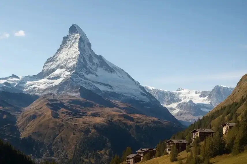 Moderne Hochhaus-Silhouette vor schneebedeckter alpiner Berglandschaft bei Tageslicht.