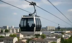 Urbane Seilbahnkabinen über einer europäischen Stadt mit Wohnhäusern und Verkehrswegen.