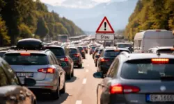 Mehrspurige Autobahn mit dichtem Pkw-Verkehr bei Tageslicht, zahlreiche Fahrzeuge mit eingeschalteten Bremslichtern.