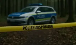 Polizeiauto im Wald hinter gelbem Absperrband, unscharfer Hintergrund mit Bäumen.