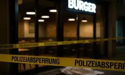 Polizeiband vor einem beleuchteten Burgerrestaurant bei Nacht, Stühle im Innenraum sichtbar, Szene ohne Personen.