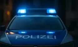 Frontalansicht eines Polizeiautos mit blauem Blaulicht in nächtlicher Umgebung, ohne erkennbare Personen oder weitere Details.