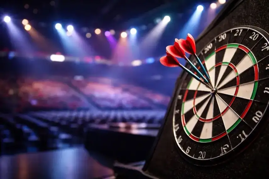 Dartboard mit gesteckten Pfeilen in einer beleuchteten Turnierhalle während der Darts-WM im Alexandra Palace