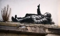 Schwarz-weißes Graffiti mit zwei liegenden Kindern an einer Ziegelwand in London, aufgenommen bei Tageslicht im urbanen Umfeld