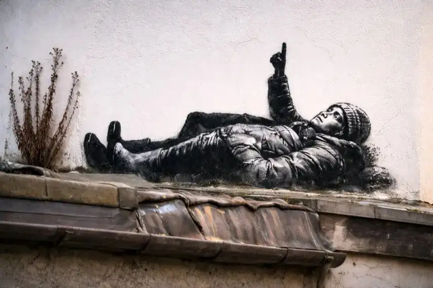 Schwarz-weißes Graffiti mit zwei liegenden Kindern an einer Ziegelwand in London, aufgenommen bei Tageslicht im urbanen Umfeld