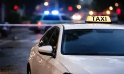 Beschädigtes Taxi mit Einschusslöchern auf einer abgesperrten Straße in Düsseldorf, Polizeilichter spiegeln sich auf der Fahrbahn.