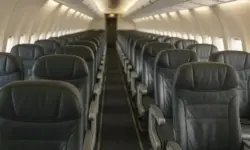 Leere Sitzreihe in einer Flugzeugkabine mit geöffnetem Gepäckfach und klarer Tiefenschärfe, ohne abgebildete Personen.