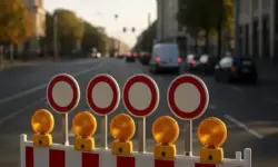 Straßensperren mit Absperrgittern, Verkehrskegeln und Polizeiabsperrband auf einer leeren Stadtstraße bei Tageslicht.