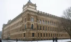 Historisches Gerichtsgebäude in Dresden im Winter, mit Schnee, kahlen Bäumen und einigen vorbeilaufenden Personen auf dem Gehweg.