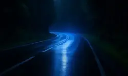 Nächtliche kurvige Landstraße im Schwarzwald mit feuchtem Asphalt und Blaulichtreflexen ohne Menschen oder Fahrzeuge.