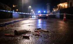 Abgesperrte Straße bei Nacht mit Blaulicht und Feuerwerksresten auf nassem Asphalt in Bielefeld nach einem Pyrotechnik-Unfall