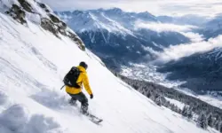 Steiler verschneiter Berghang mit Snowboarder in den Schweizer Alpen oberhalb eines Wintersportorts bei winterlichen Bedingungen