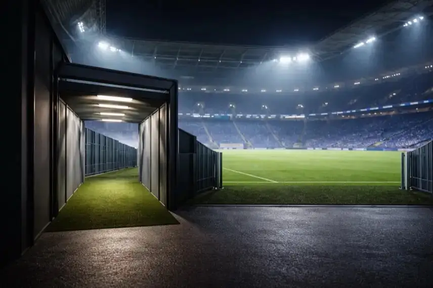 Nächtlich beleuchtetes Fußballstadion mit offenem Spielertunnel und Flutlichtmasten als Hintergrund, ruhige Atmosphäre ohne Menschen