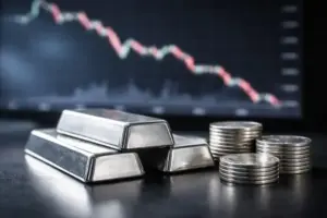 Silberbarren auf dunkler Oberfläche vor unscharfem Börsenchart mit fallender Linie, Darstellung des Silberpreises und der Marktentwicklung