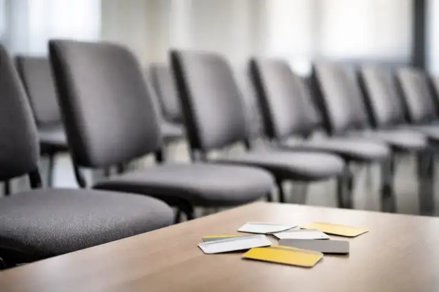 Leere Stühle in einem neutralen Raum, davor mehrere unbeschriftete Karten auf einem Tisch, sachliche Lichtstimmung, Symbol für ADAC Austritte