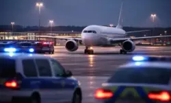 Passagierflugzeug steht bei Dämmerung auf dem Flughafen München, im Hintergrund Startbahn und Einsatzfahrzeuge mit Blaulicht.