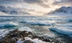 Eisbedeckte Küstenlandschaft in Grönland mit Felsen, Meereseis und bewölktem Himmel in der Arktis