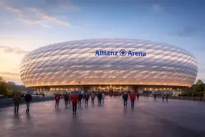 Außenansicht der Allianz Arena in München bei Abenddämmerung mit beleuchteter Stadionfassade und Vorplatz