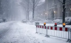 Verschneite Straße in Hannover mit abgesperrtem öffentlichen Gebäude, Glätte und starkem Schneefall während eines Wintersturms.