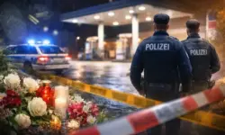 Nächtliche Tankstelle in Völklingen mit Absperrband und blauem Polizeilicht auf nassem Asphalt, Personen sichtbar.
