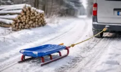Schlitten an Auto befestigt auf verschneitem Feldweg nahe Holzstapel im Landkreis Rostock