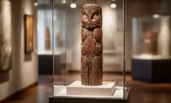 Geschnitztes Holzobjekt auf einem Podest in einem neutralen Museumsraum, gleichmäßig ausgeleuchtet, ohne Personen oder Beschriftungen.