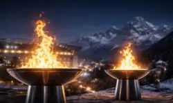 Zwei olympische Feuerschalen brennen nachts, eine vor städtischer Kulisse, eine vor alpinen Bergen, als Symbol für die Winterspiele 2026.