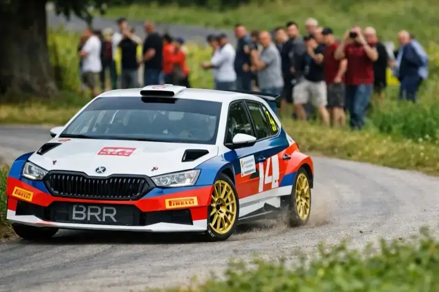 Beschädigtes Rallyeauto nach Unfall in steilem Gelände neben Bergstraße, Rettungshubschrauber und Einsatzkräfte bei Rallye in Österreich