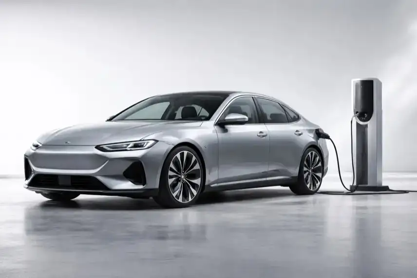 Moderne elektrische Limousine an Ladestation, futuristisches Auto mit aerodynamischem Design, Elektroauto Mittelklasse Reichweite 900 km