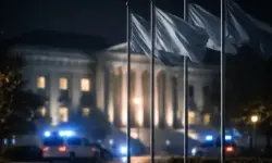 Flaggenmasten vor Regierungsgebäude bei Nacht mit Blaulicht als Symbol für NATO-Spannungen und transatlantische Unsicherheit