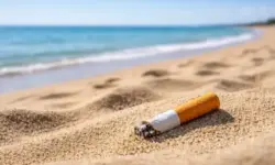 Zigarettenstummel im Sand an einem sauberen Strand an der Adriaküste, ruhiges Meer im Hintergrund