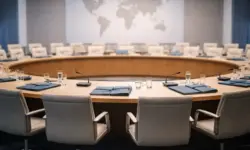 Leerer Sitzungssaal mit rundem Tisch und Weltkarte als Symbol für Vereinte Nationen und Völkerrecht im Iran-Krieg