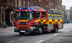 Feuerwehrfahrzeuge vor beschädigtem Gebäude nahe Bahnhof nach Brand in Innenstadt mit gesperrter Straße und Einsatzkräften