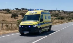 Beschädigte Autos nach Frontalcrash auf Landstraße in Portugal, Unfallstelle mit Trümmern und Blaulicht im Hintergrund