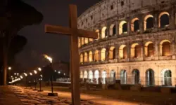Kreuzweg am Kolosseum bei Nacht, beleuchtetes Amphitheater und getragenes Holzkreuz in ruhiger Prozession